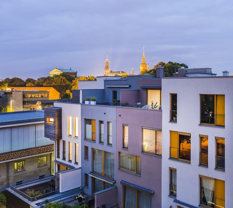 Abendaufnahme moderner Stadtwohnungen mit Blick auf historische Skyline Dresden im Hintergrund