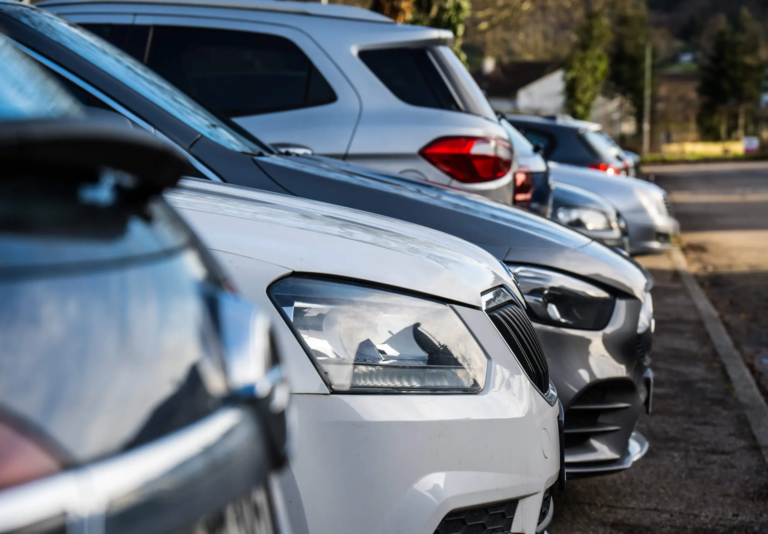 Geparkte Autos nebeneinander in einer Wohnstraße bei Sonnenschein