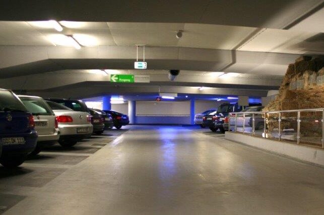 Zufahrt zur Tiefgarage vor moderner Wohnanlage mit weißen Mehrfamilienhäusern