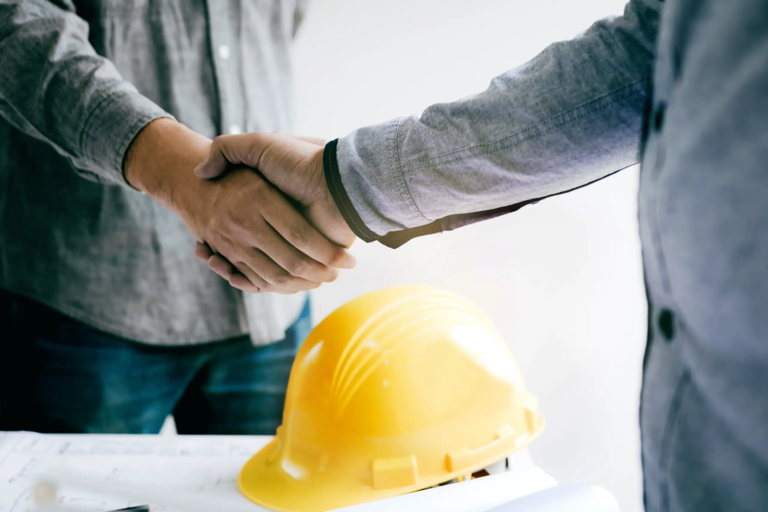 Handschlag über Bauhelm – Symbol für Kooperation im Immobilienwesen